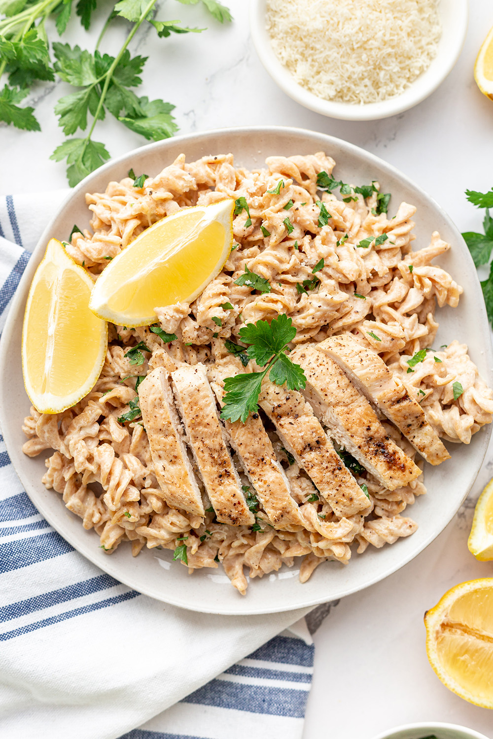 Creamy Cauliflower Rotini pasta is topped with pan-seared chicken breast and parmesan cheese